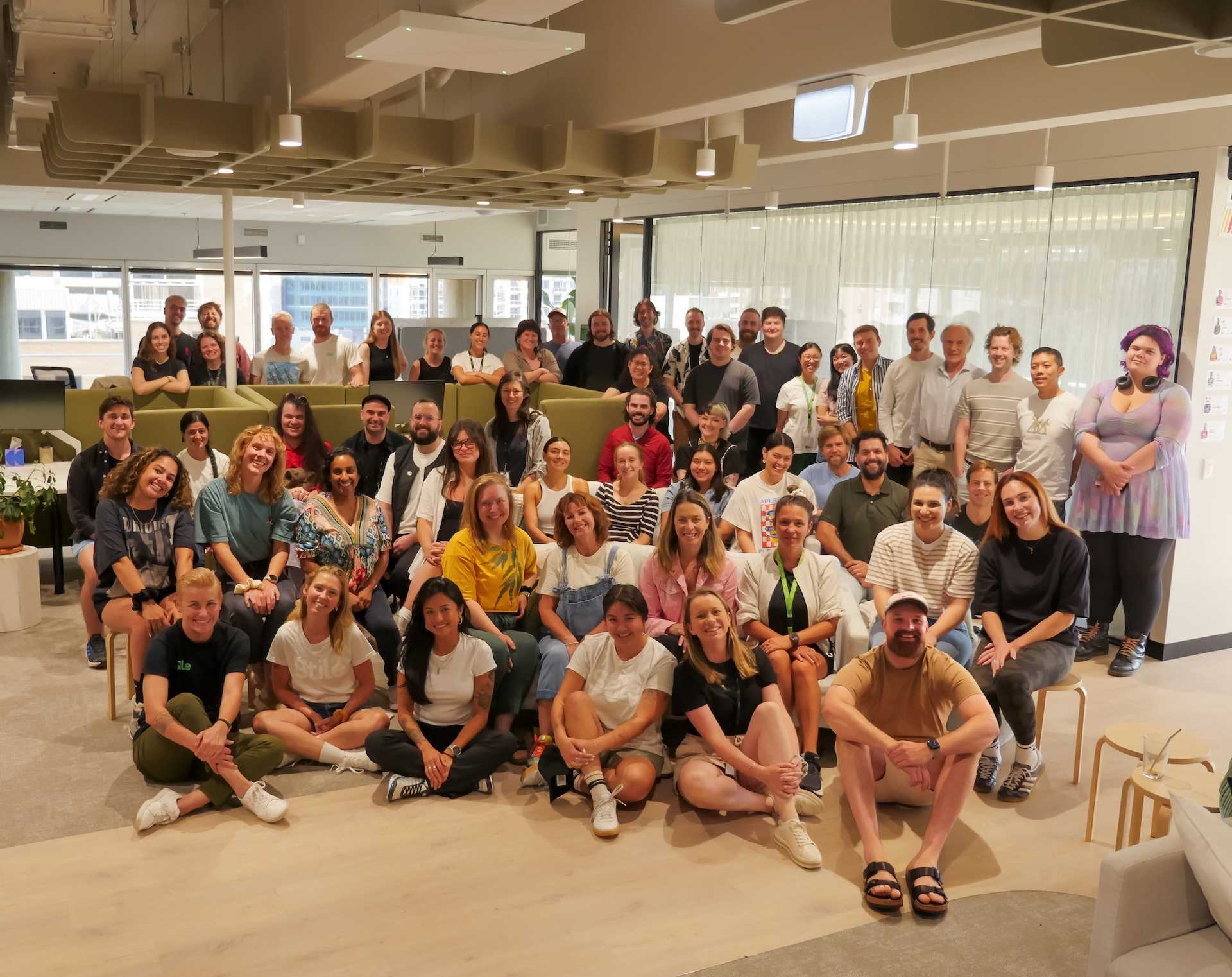 The whole Stile team are standing together in an extended lounge area with an office backdrop.