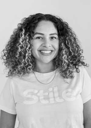 A black & white portrait of Stile team member Julianna Jimenez smiling at the camera