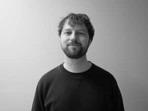 A black & white portrait of Stile team member Jack Brock smiling at the camera