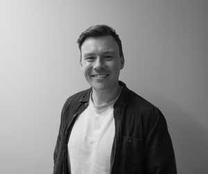 A black & white portrait of Stile team member Tom Grubb smiling at the camera