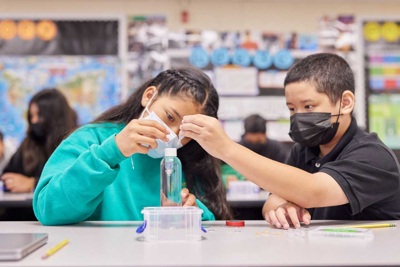 Two students conduct an experiment together in their classroom