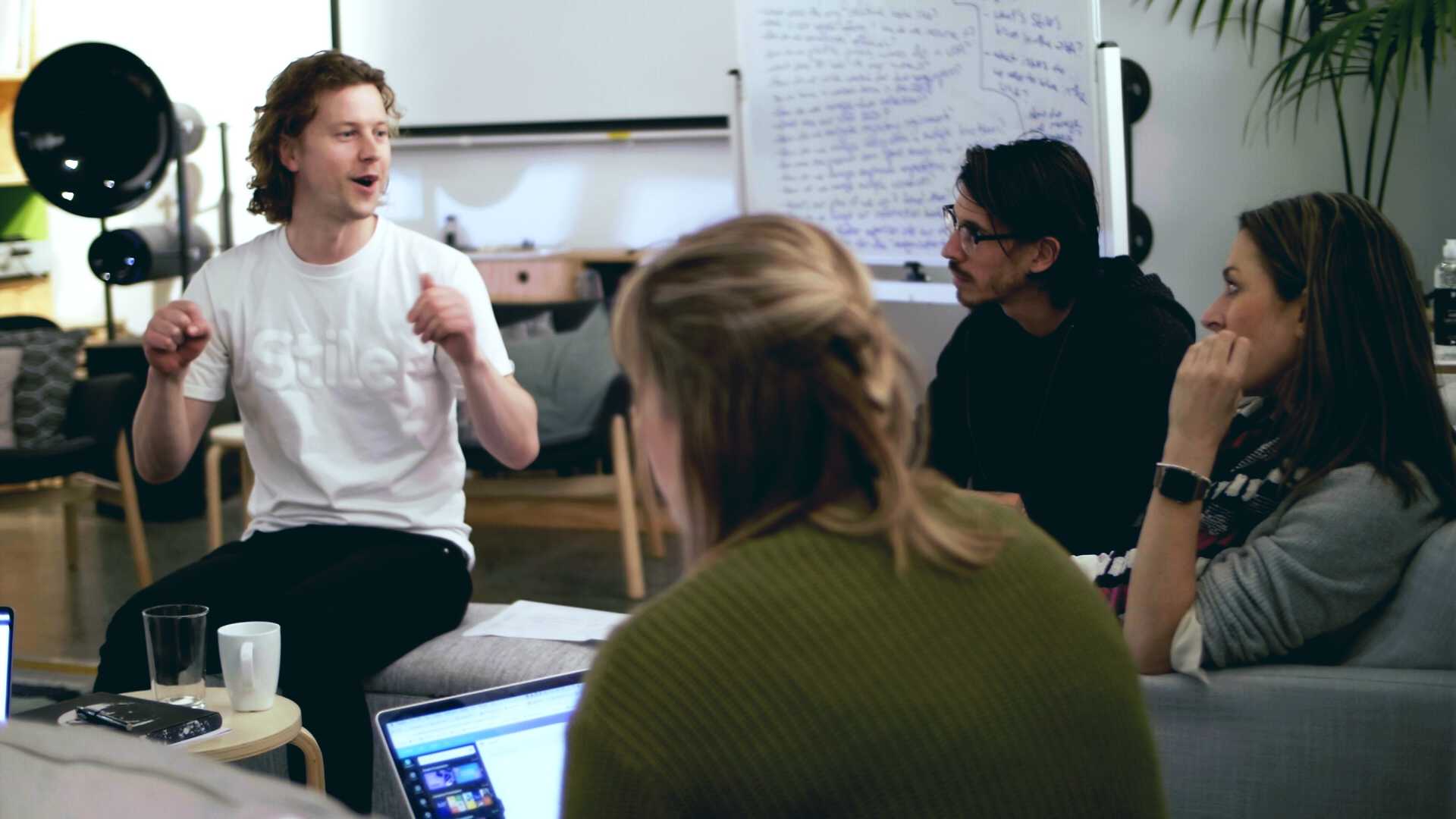 Several Stile staff members sitting in a relaxed meeting area. One is explaining something and the others are listening attentively