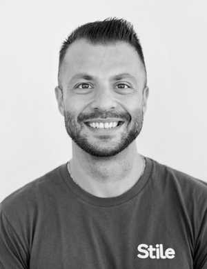 A black & white portrait of Stile team member Mark Picardo smiling at the camera