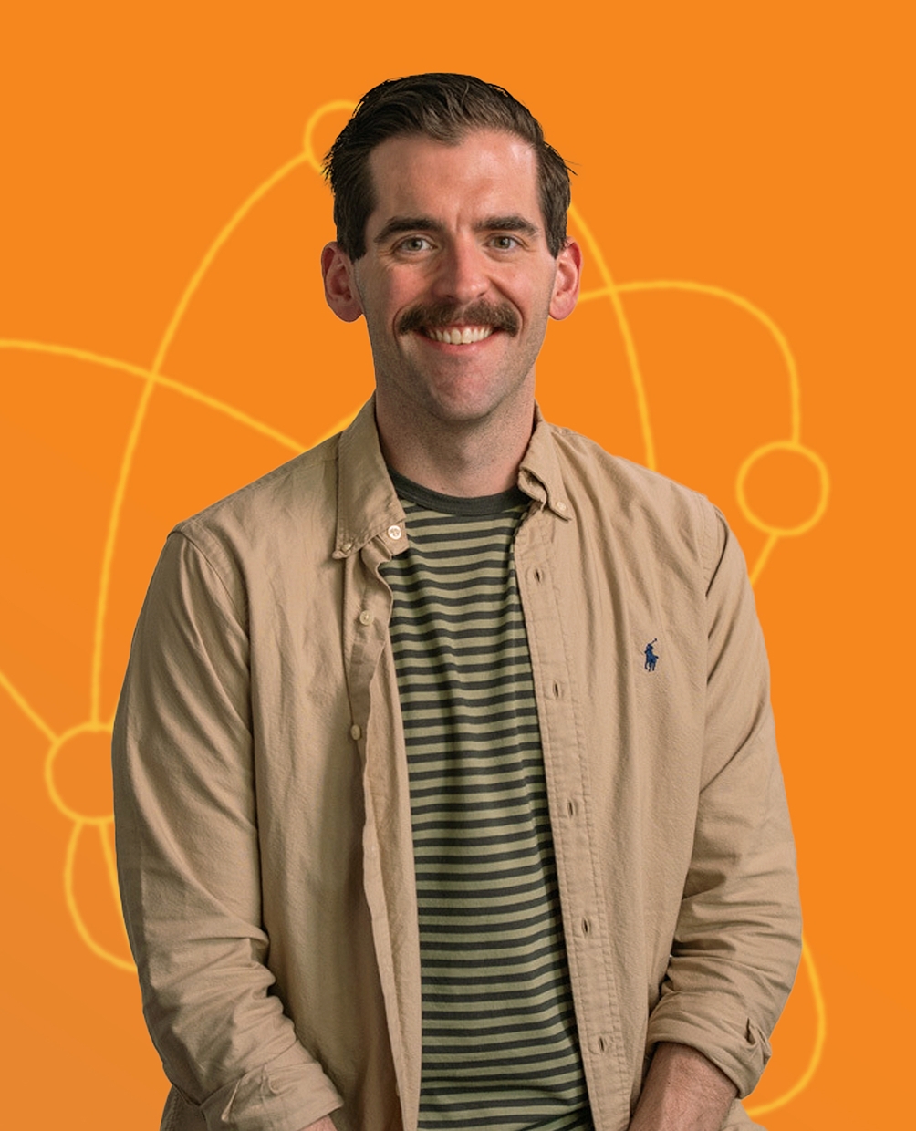 A man smiling in front of a bright orange background with stylised atom illustrations. He wears a striped shirt and an open button-down top.