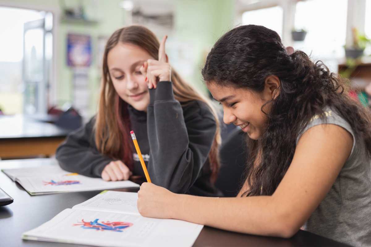 Two students collaborating over schoolwork in a classroom.