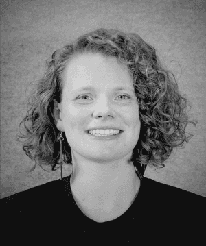 A black & white portrait of Stile team member Gisela Beer smiling at the camera