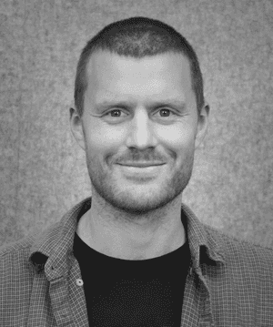 A black & white portrait of Stile team member Hamish McCoy smiling at the camera
