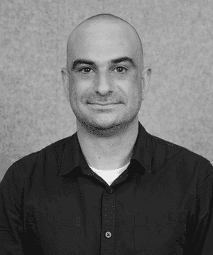 A black & white portrait of Stile team member Paul Giardina smiling at the camera
