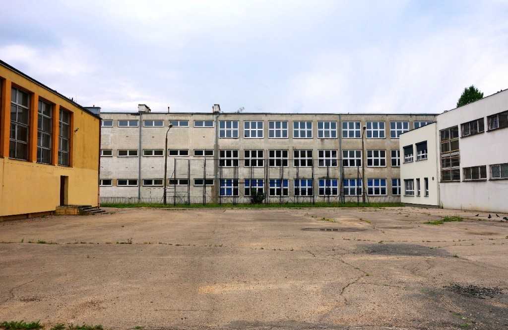 A large paved urban yard surrounded by concrete buildings, illustrating the urban heat island lesson in Stile.